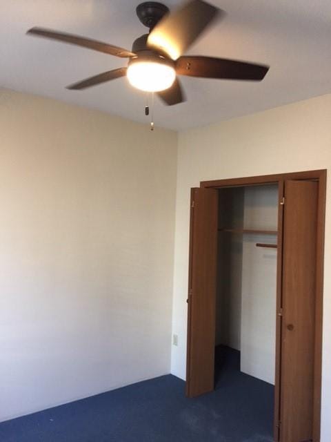 unfurnished bedroom with a closet, dark carpet, and ceiling fan