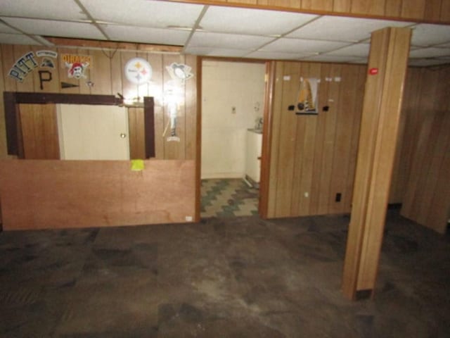 basement with a paneled ceiling and wooden walls