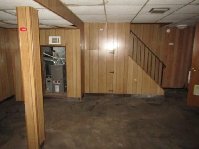 basement with a paneled ceiling and wood walls