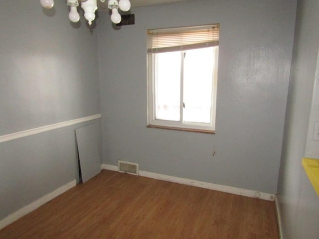 empty room with a notable chandelier and hardwood / wood-style floors