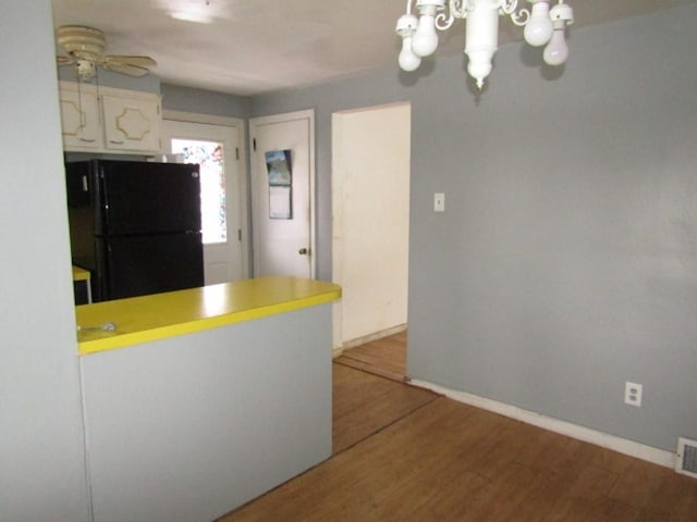 kitchen with black refrigerator, white cabinets, wood-type flooring, and ceiling fan