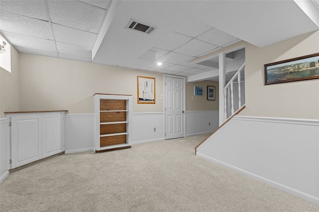 basement featuring light carpet and a drop ceiling