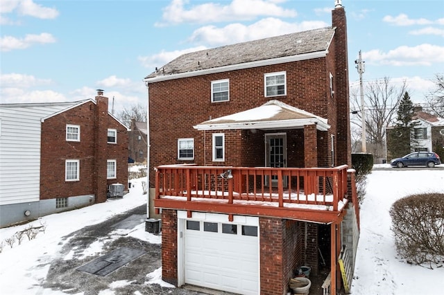 snow covered rear of property with a garage