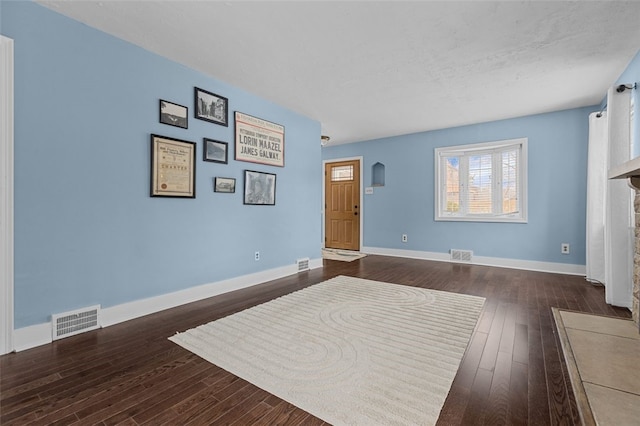 interior space with a tiled fireplace and dark wood-type flooring