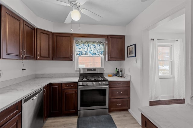 kitchen with light stone countertops, stainless steel appliances, light hardwood / wood-style floors, ceiling fan, and dark brown cabinetry