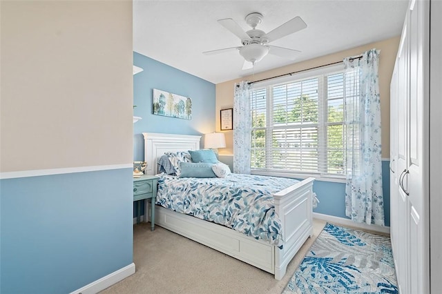 bedroom featuring light colored carpet, ceiling fan, and a closet