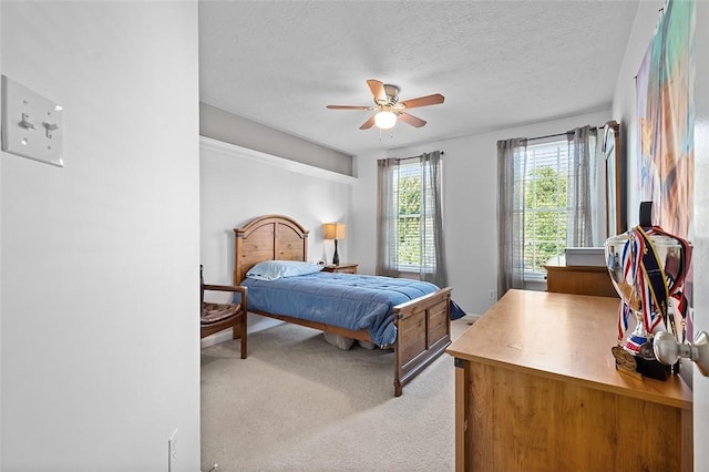 bedroom with a textured ceiling, ceiling fan, and light colored carpet