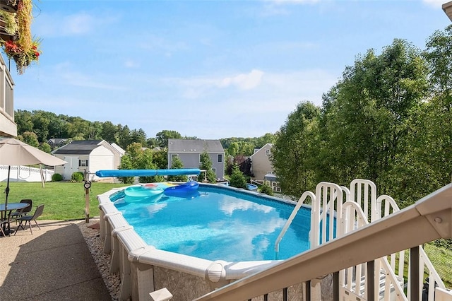 view of pool with a yard and an outbuilding