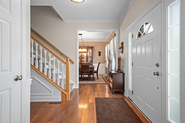 entrance foyer featuring ornamental molding, a chandelier, and hardwood / wood-style flooring