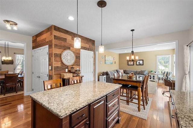 kitchen featuring a wealth of natural light, a center island, hardwood / wood-style floors, and wood walls