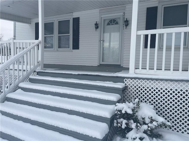 snow covered property entrance featuring covered porch