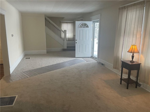 foyer entrance with stairs, visible vents, baseboards, and carpet flooring