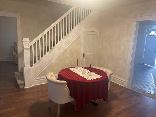 dining space featuring baseboards, dark wood-type flooring, and stairs