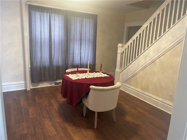 dining area with stairs, dark wood-type flooring, and baseboards