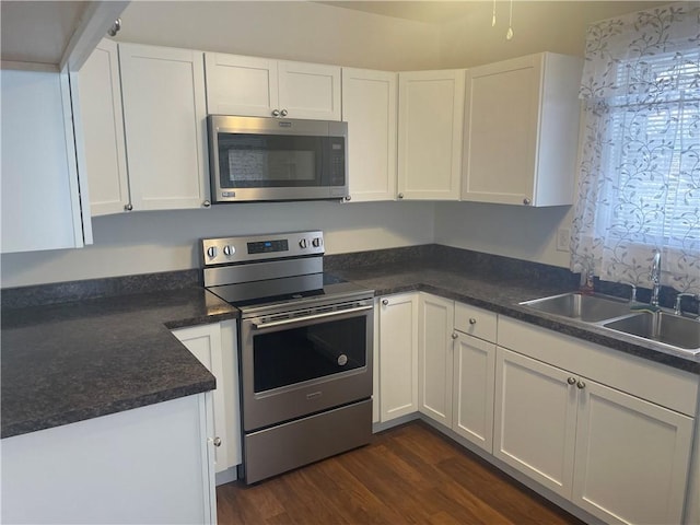 kitchen with dark wood-style flooring, white cabinets, appliances with stainless steel finishes, and a sink