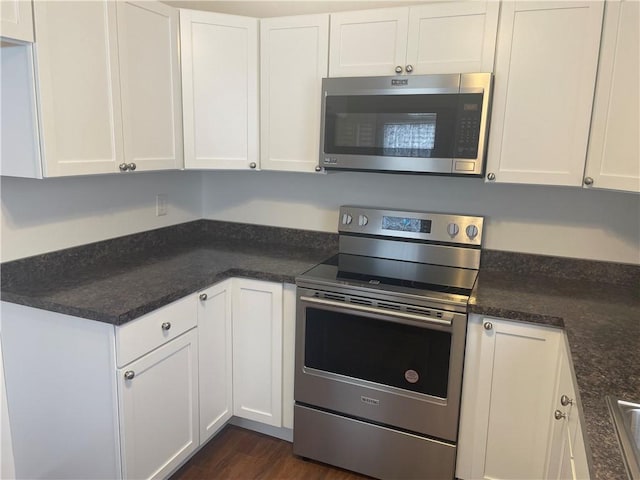 kitchen with appliances with stainless steel finishes, dark wood finished floors, and white cabinetry