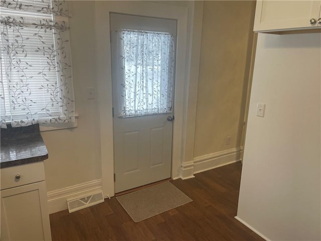 foyer entrance featuring visible vents, dark wood-type flooring, and baseboards