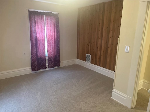 carpeted spare room with visible vents and baseboards