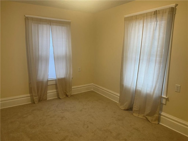 carpeted empty room featuring baseboards and plenty of natural light