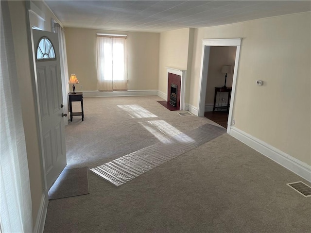 interior space with carpet flooring, a fireplace with flush hearth, baseboards, and visible vents