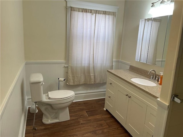 bathroom featuring vanity, toilet, wood finished floors, and a wainscoted wall