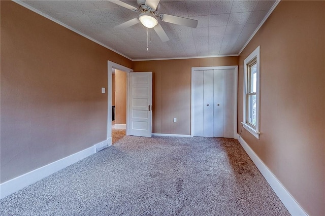 unfurnished bedroom featuring ornamental molding, a closet, ceiling fan, and carpet