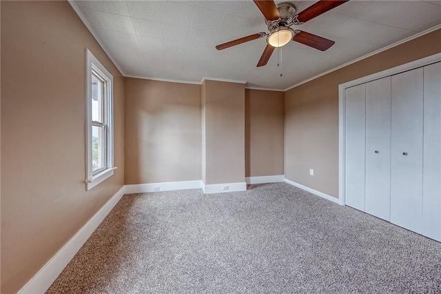 unfurnished bedroom with crown molding, a closet, ceiling fan, and carpet flooring