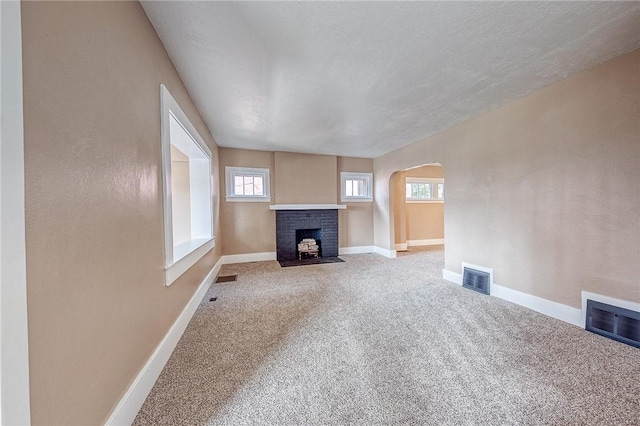 unfurnished living room featuring a brick fireplace, carpet floors, and a textured ceiling