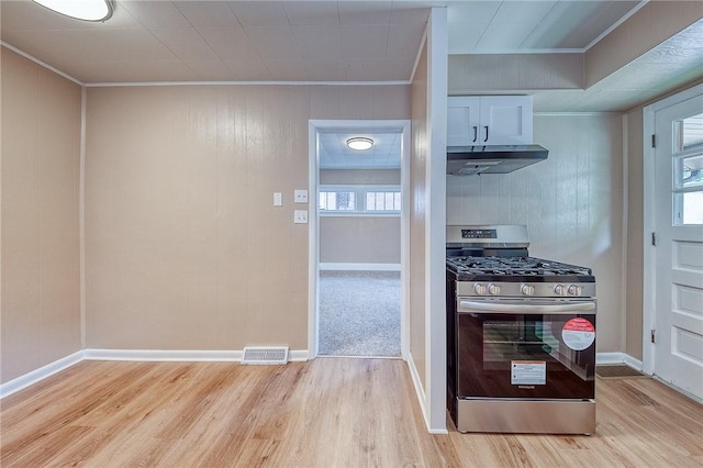 kitchen with white cabinetry, ornamental molding, light wood-type flooring, and stainless steel gas range oven