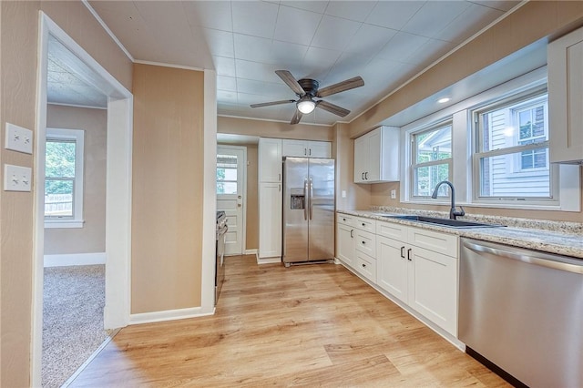 kitchen with stainless steel appliances, sink, white cabinets, and light stone counters