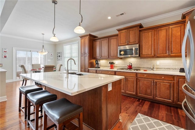 kitchen featuring sink, pendant lighting, dark hardwood / wood-style flooring, a kitchen island with sink, and appliances with stainless steel finishes