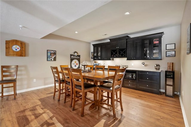 dining space featuring beverage cooler, light hardwood / wood-style floors, and indoor bar