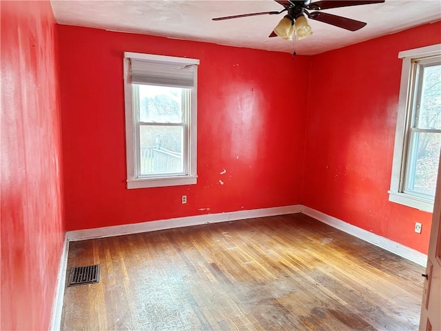 empty room featuring ceiling fan, a wealth of natural light, and hardwood / wood-style flooring