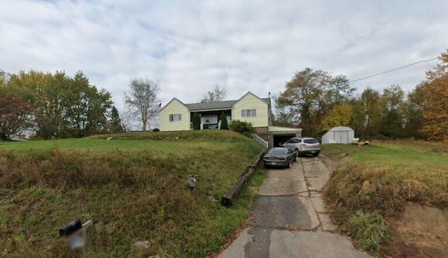 view of front of property featuring a front yard and a storage shed