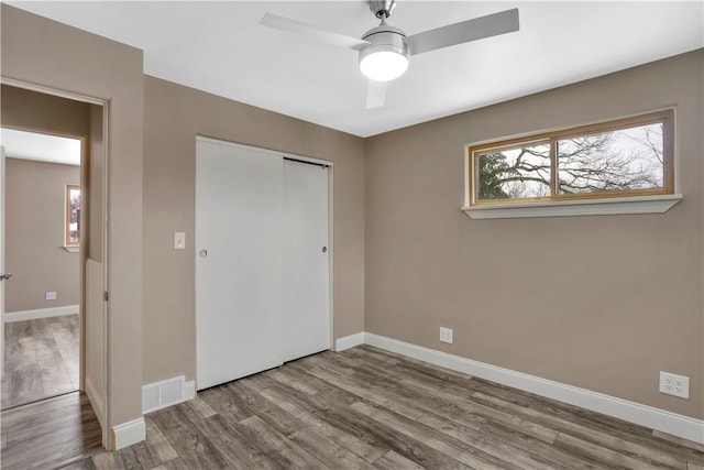 unfurnished bedroom featuring ceiling fan, a closet, and light wood-type flooring