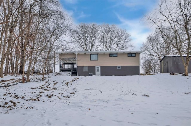 snow covered back of property featuring a wooden deck