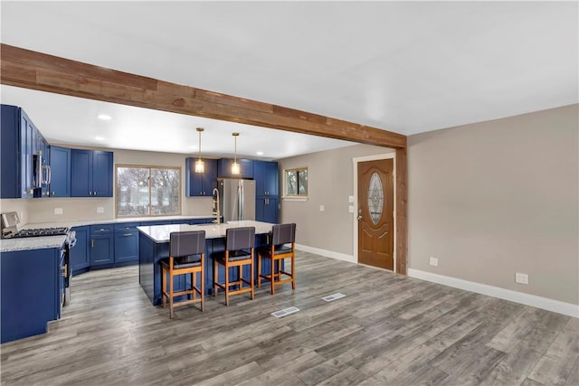 kitchen featuring a kitchen island, beam ceiling, hardwood / wood-style flooring, appliances with stainless steel finishes, and blue cabinets