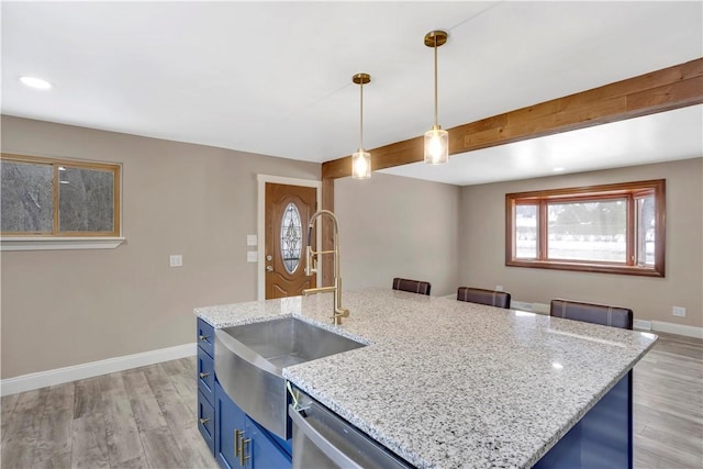 kitchen featuring a kitchen island with sink, blue cabinets, dishwasher, pendant lighting, and sink