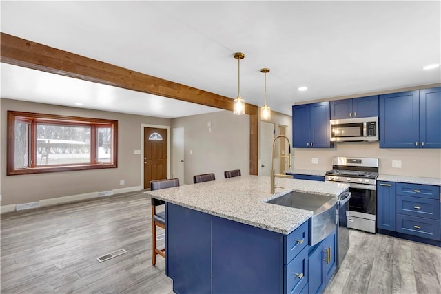 kitchen featuring a kitchen island with sink, a kitchen bar, blue cabinets, and stainless steel appliances