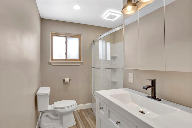 bathroom featuring a shower with shower door, hardwood / wood-style flooring, vanity, and toilet