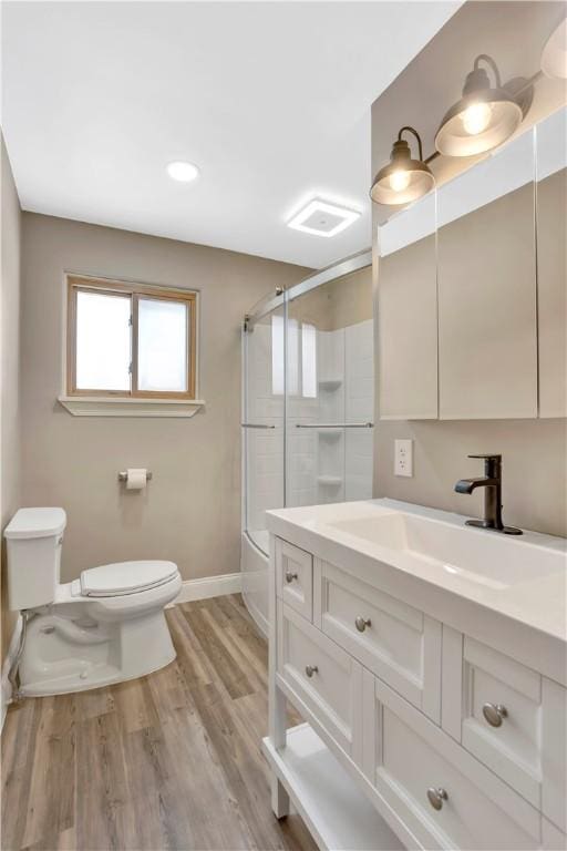 full bathroom featuring toilet, bath / shower combo with glass door, vanity, and hardwood / wood-style floors