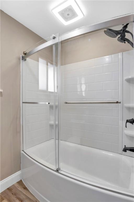 bathroom with bath / shower combo with glass door and hardwood / wood-style floors