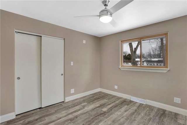 unfurnished bedroom featuring ceiling fan, a closet, and light hardwood / wood-style floors