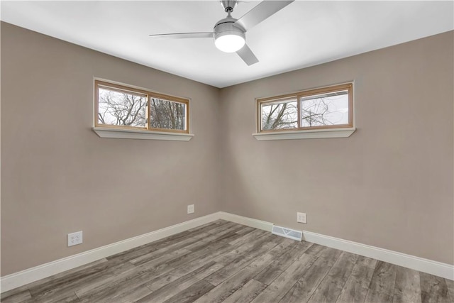 empty room with wood-type flooring, a wealth of natural light, and ceiling fan