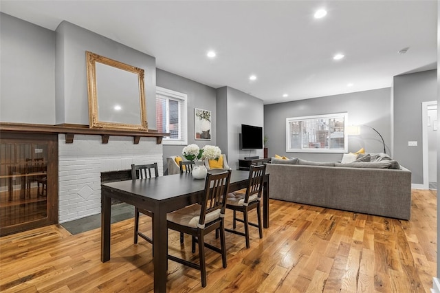 dining room featuring a brick fireplace and light wood-type flooring