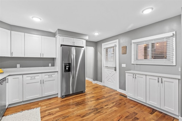 kitchen featuring appliances with stainless steel finishes, light wood-type flooring, and white cabinets