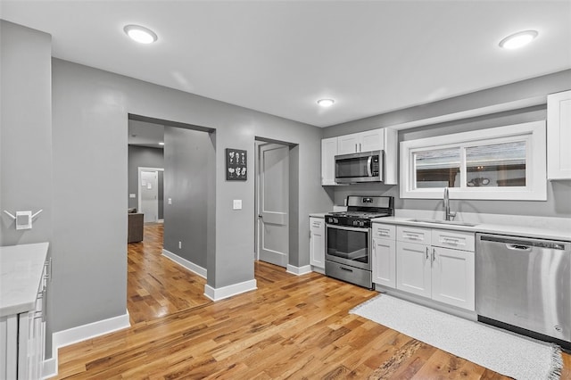 kitchen featuring appliances with stainless steel finishes, white cabinetry, and sink