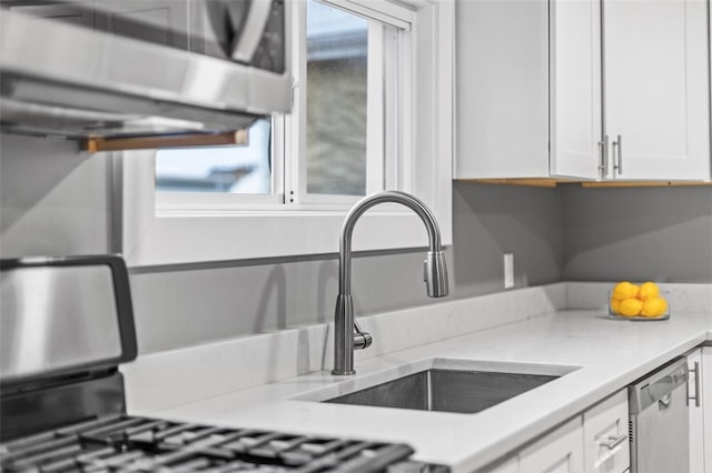 kitchen featuring sink, dishwasher, white cabinets, and a healthy amount of sunlight