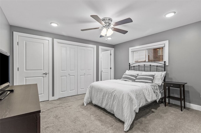 carpeted bedroom featuring ceiling fan and multiple closets