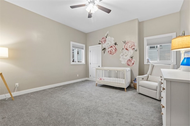 carpeted bedroom featuring a nursery area and ceiling fan